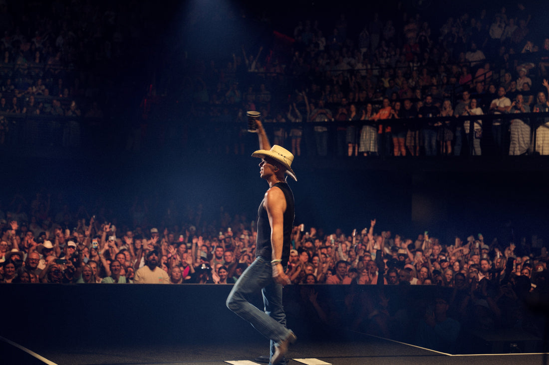 Kenny Chesney on stage at The Pinnacle Nashville holding a cup in the air